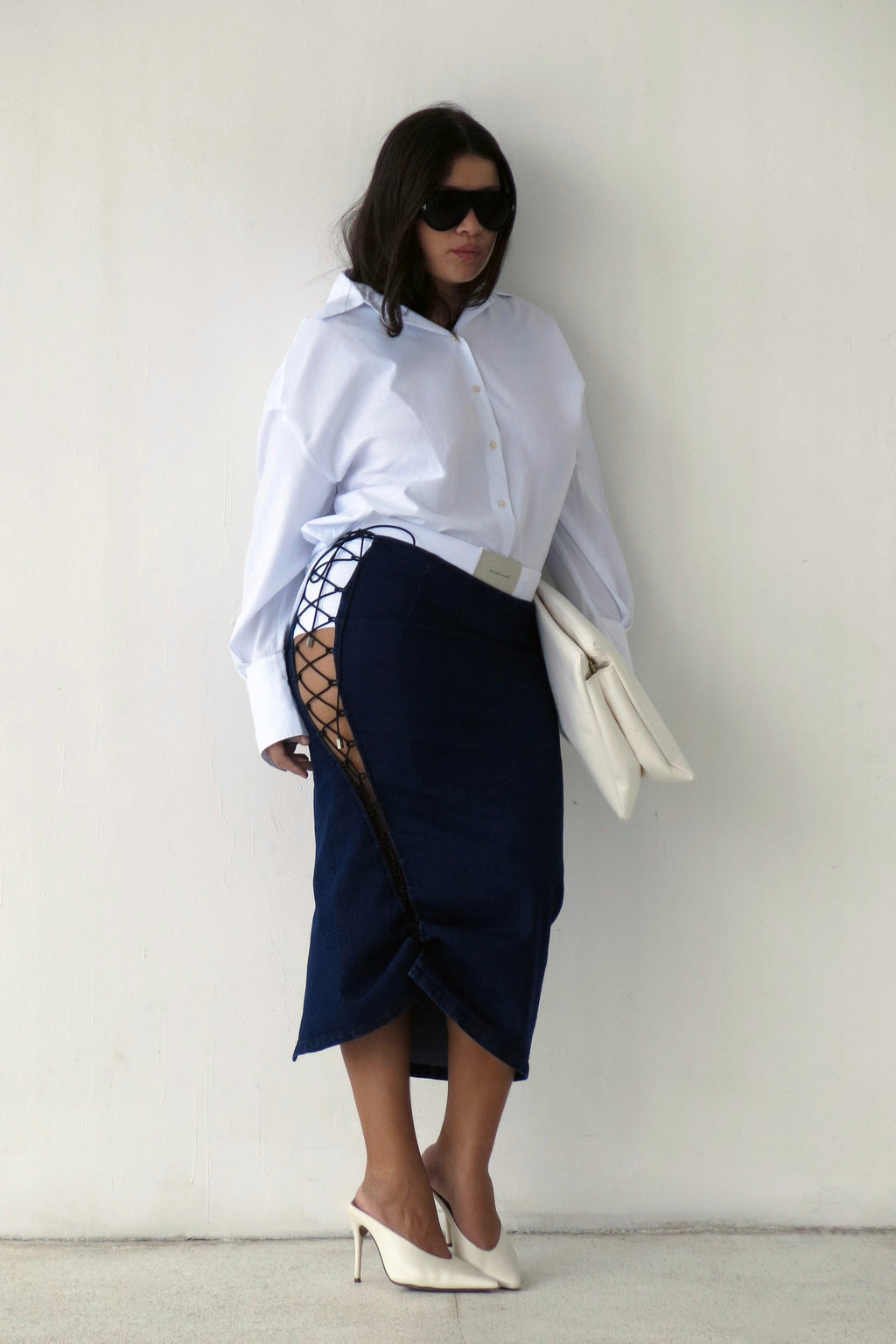 Modelo usando Saia Jeans Midi Amarrações Azul Karoline Vitto e Camisa Split Costas Branca