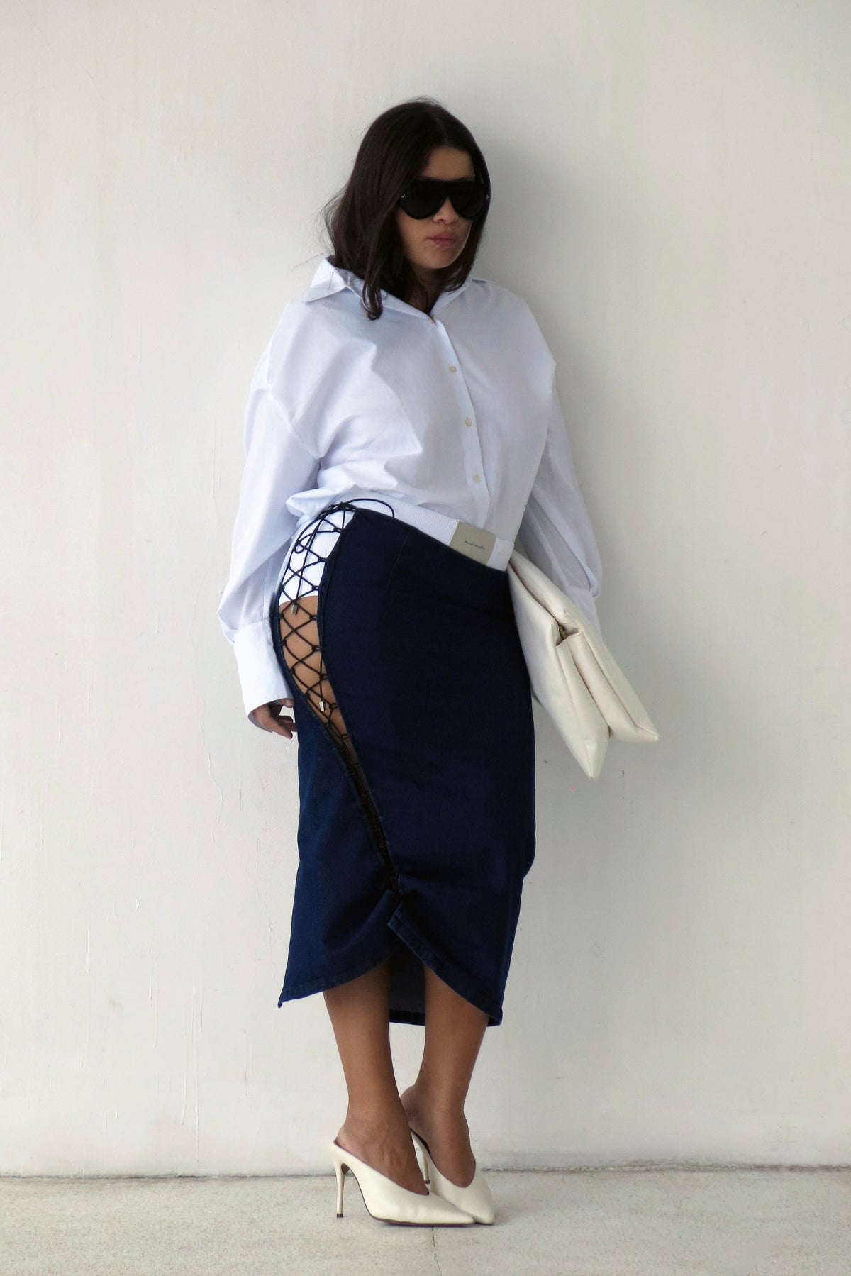 Modelo usando Saia Jeans Midi Amarrações Azul Karoline Vitto e Camisa Split Costas Branca